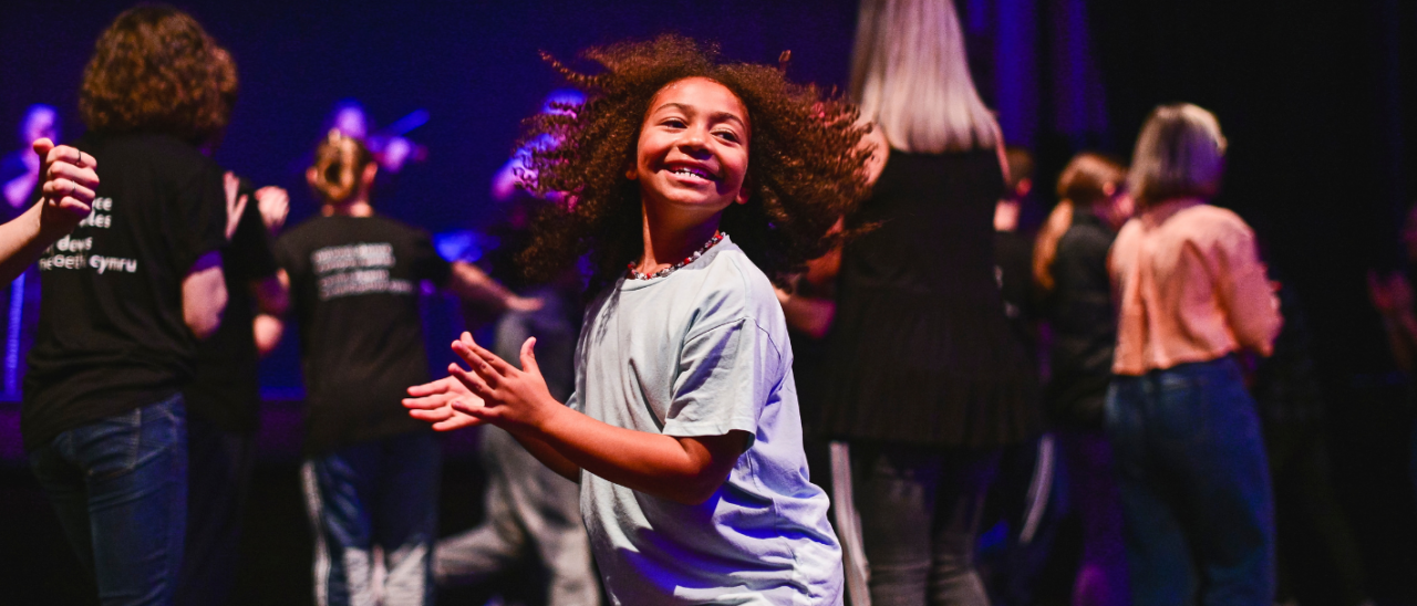 young person dancing and smiling, their hair flying out